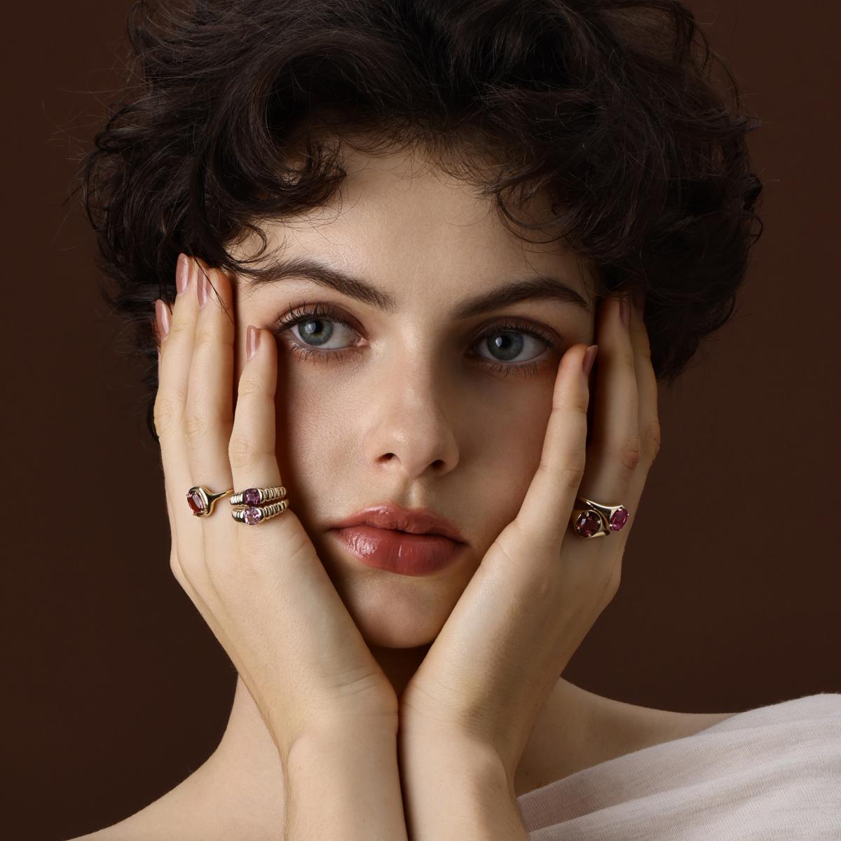 Model wearing colored gemstone rings in different shapes
