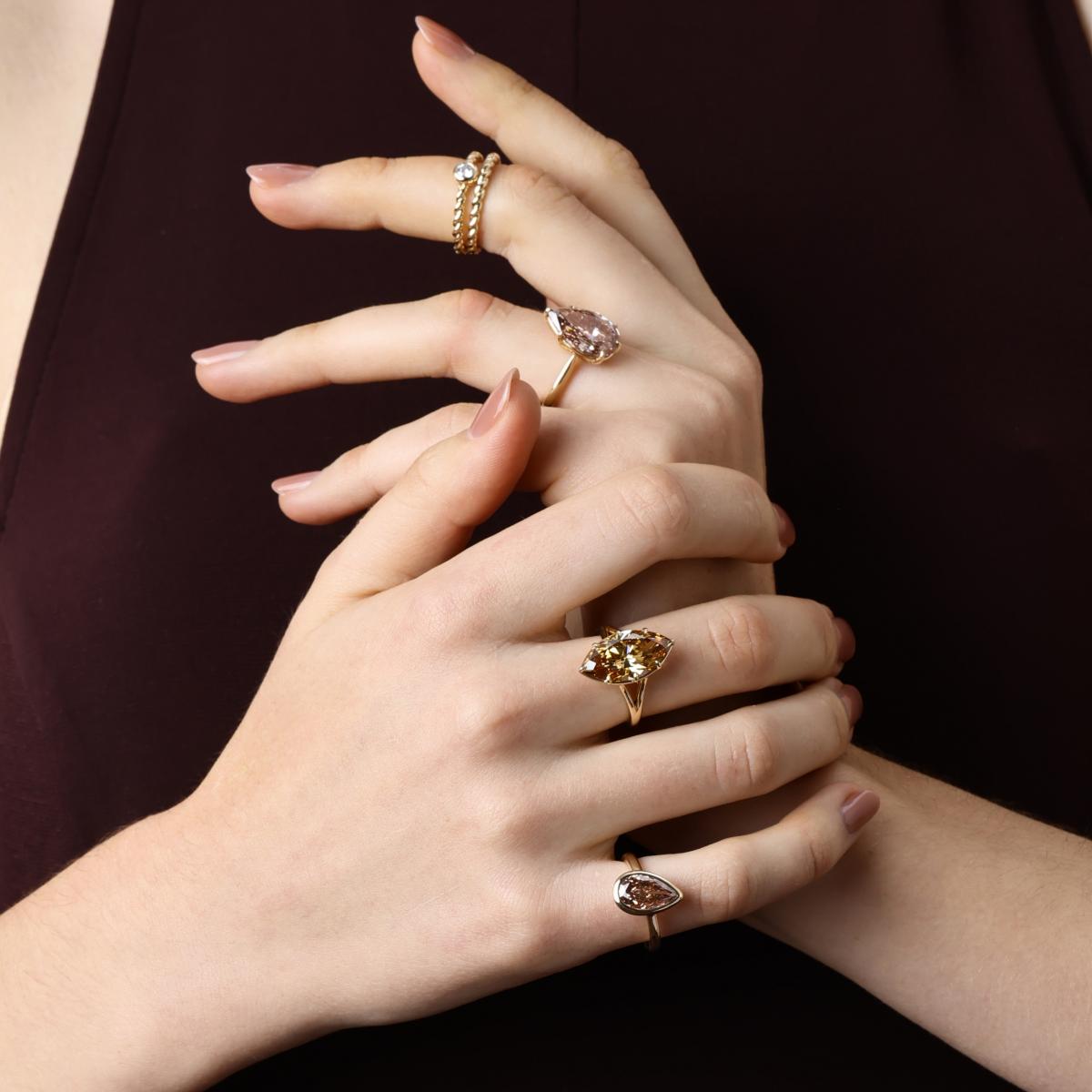 Model wearing champagne and brown lab grown diamond rings styled with gold bands