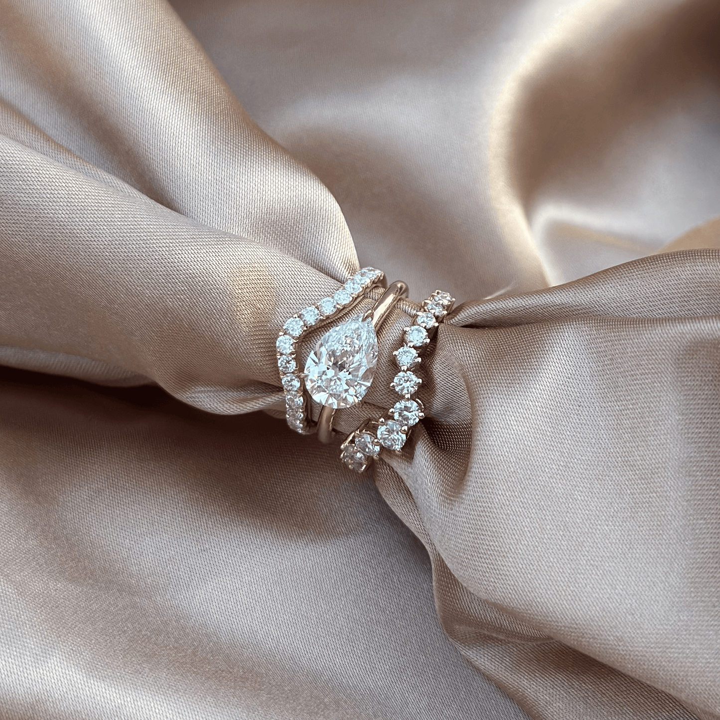 Bold stacked ring look with East-West Pear diamond ring paired with pavé and curved bands