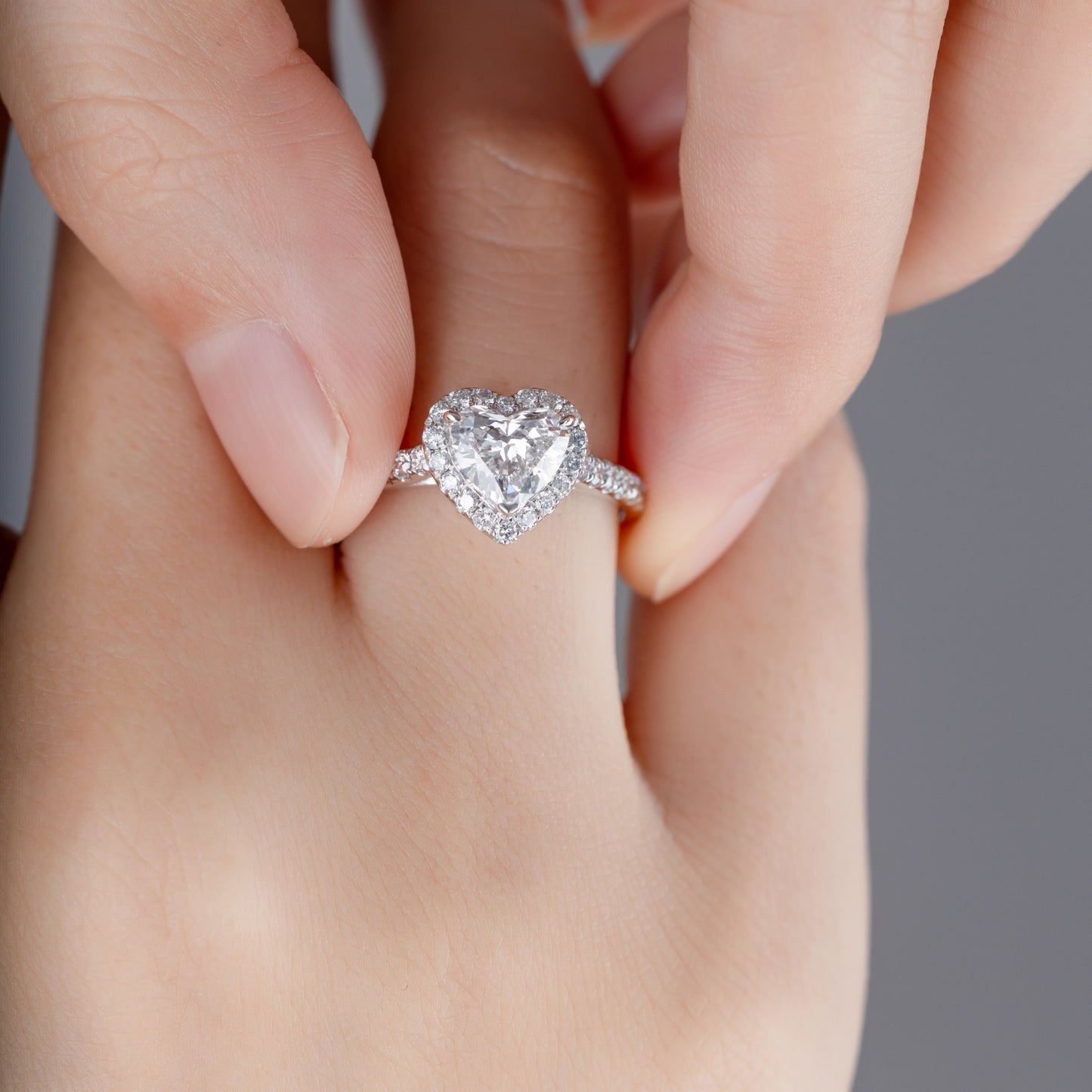 Close-up of Heart cut Lab Grown diamond in a pave setting Halo Engagement Ring on model’s finger