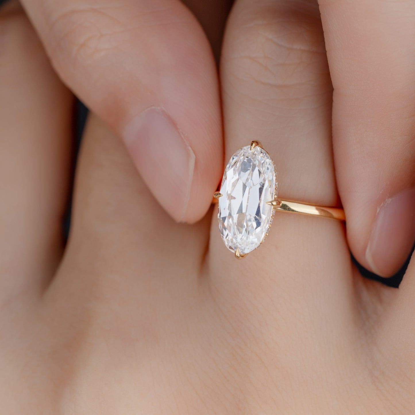 Close-up of Moval cut lab-grown diamond in four-prong setting on model’s finger