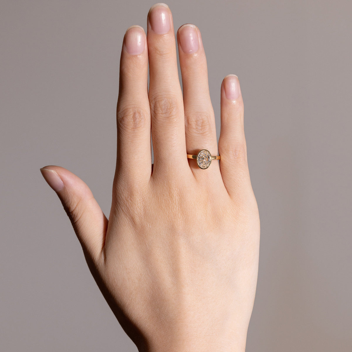 Close-up of oval-cut lab-grown diamond bezel ring reflecting light