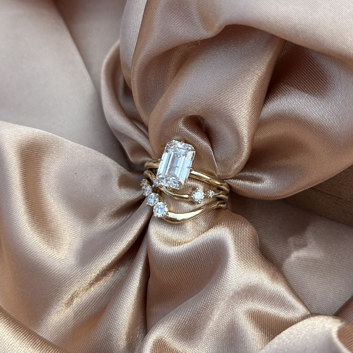 Maya ring paired with emerald engagement ring, showing curved stacking harmony