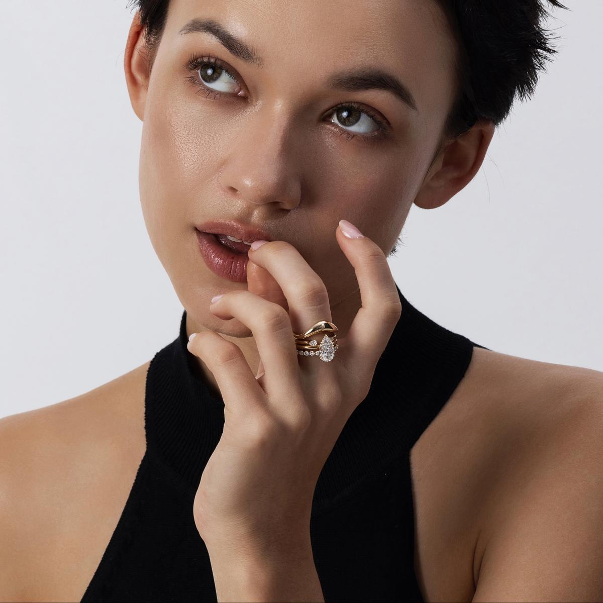 Model hand wearing a layered stack of lab-grown diamond rings in mixed gold tones