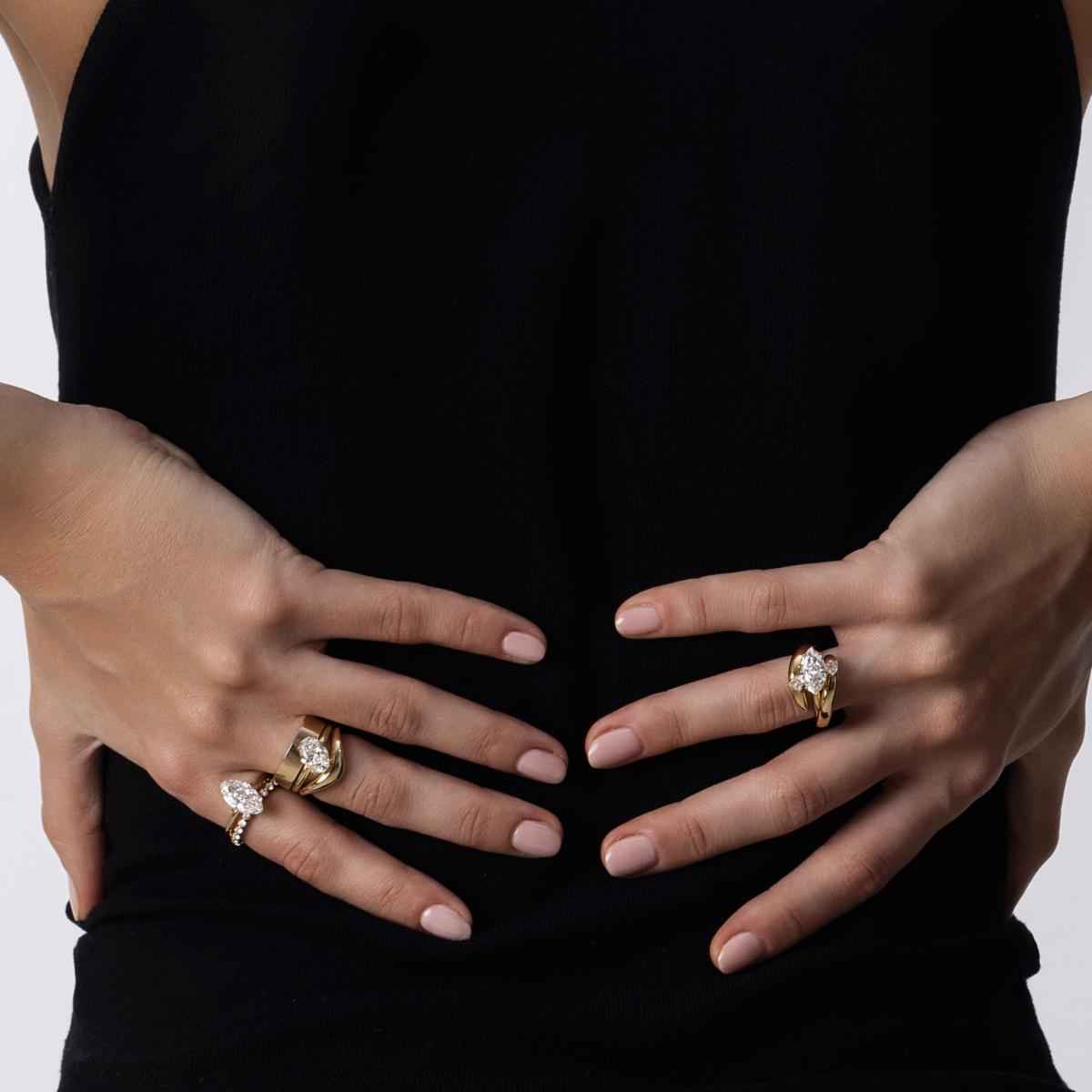 Model showcasing stacked diamond rings including the solitaire rings and curved bands, plain wide gold ring