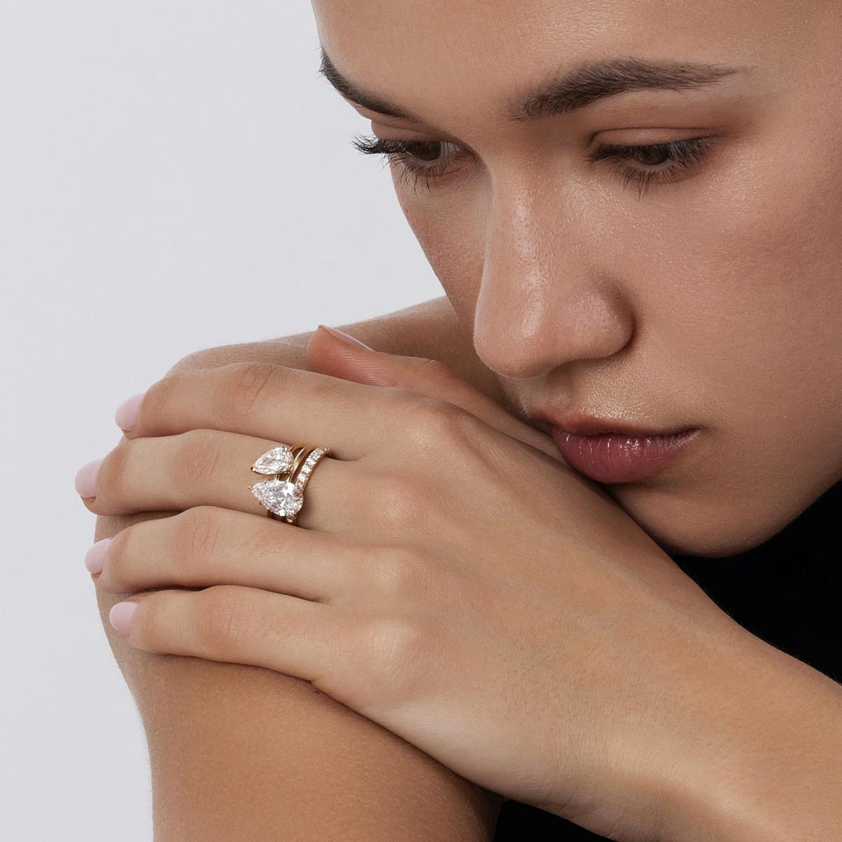 Model wearing 2 pear cut diamond rings stacked with a slim pavé band