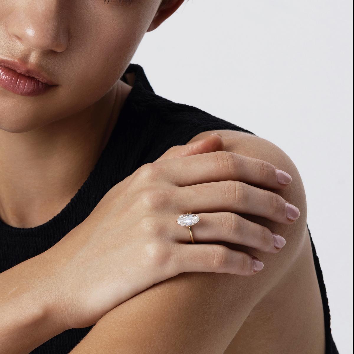 Model wearing 2ct Belle Oval cut diamond ring in arm-crossed pose