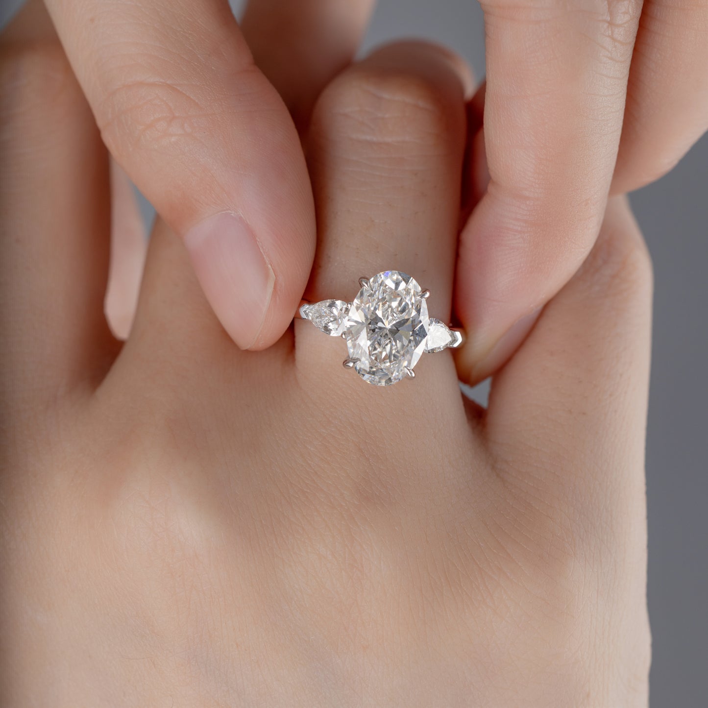 Model wearing Three-Stone Oval diamond engagement ring on ring finger