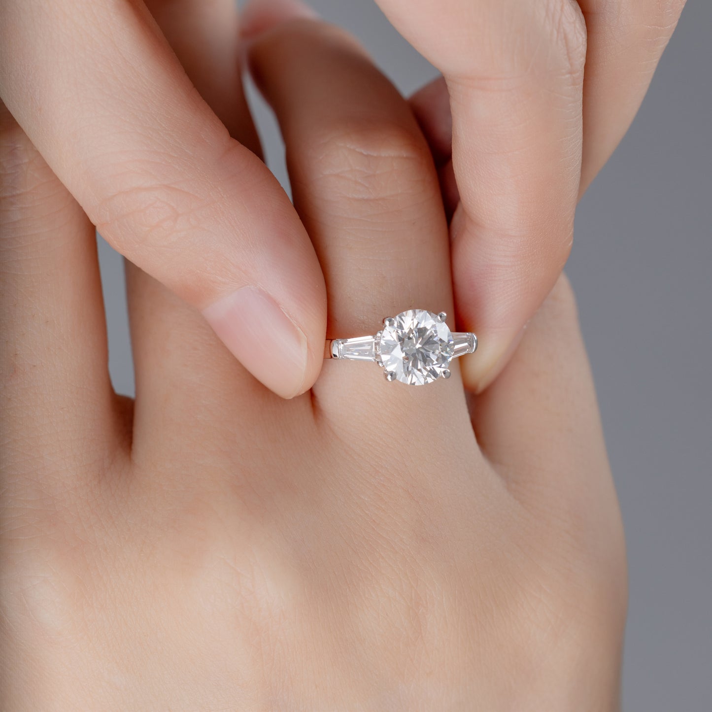 Model wearing Three-Stone Round diamond engagement ring on ring finger