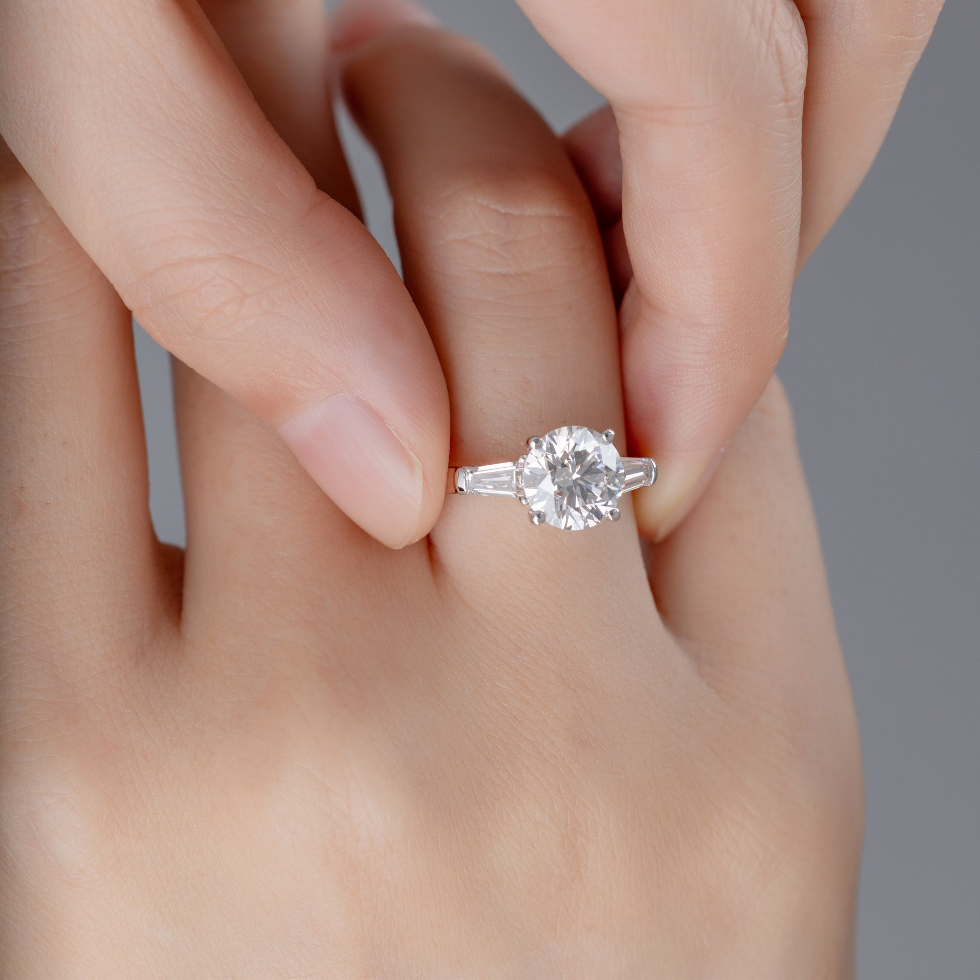 Model wearing Three-Stone Round diamond engagement ring on ring finger