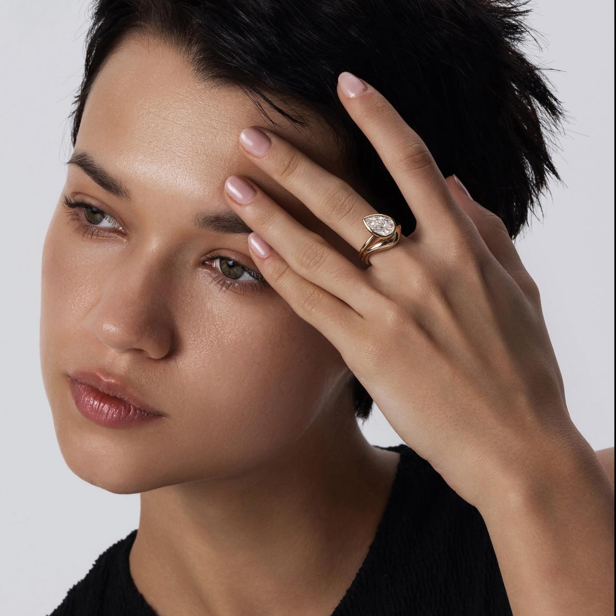 Model wearing a stacked ring look featuring a bezel-set diamond ring and complementary band