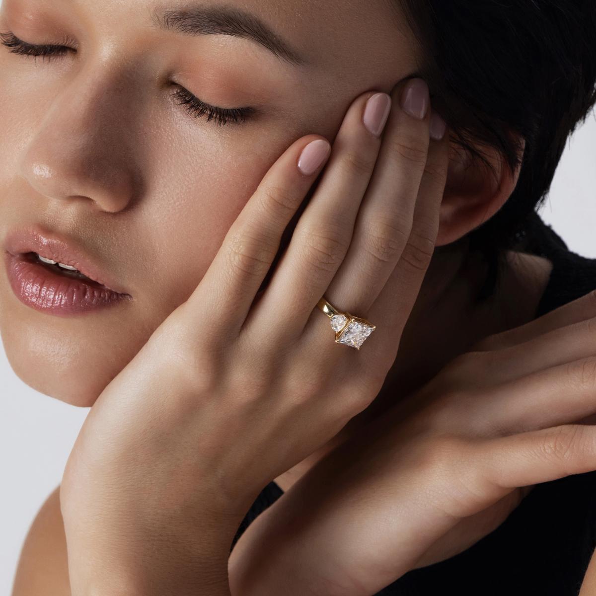 Model wearing trilogy diamond engagement ring with Princess center and half moon cut sides