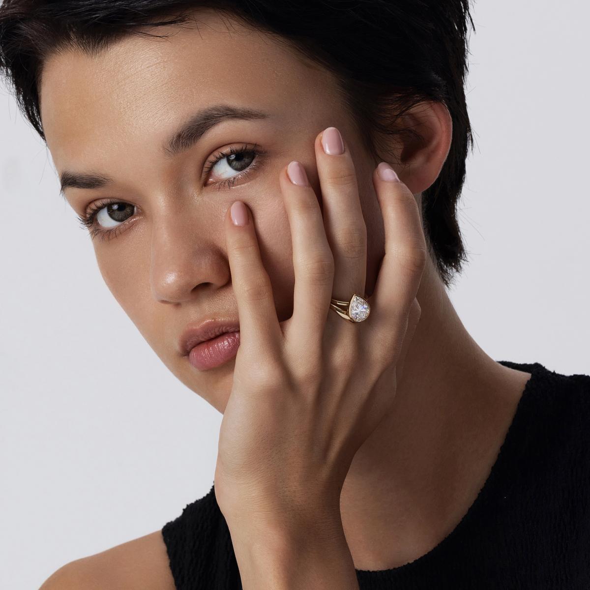 Stacked ring look featuring a tilted pear diamond ring and a delicate contour band in yellow gold