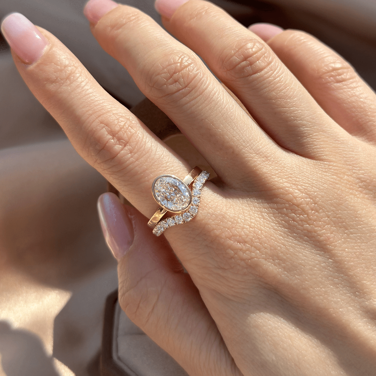 Stacking ring look of a bezel oval engagement ring and a curved pavé band