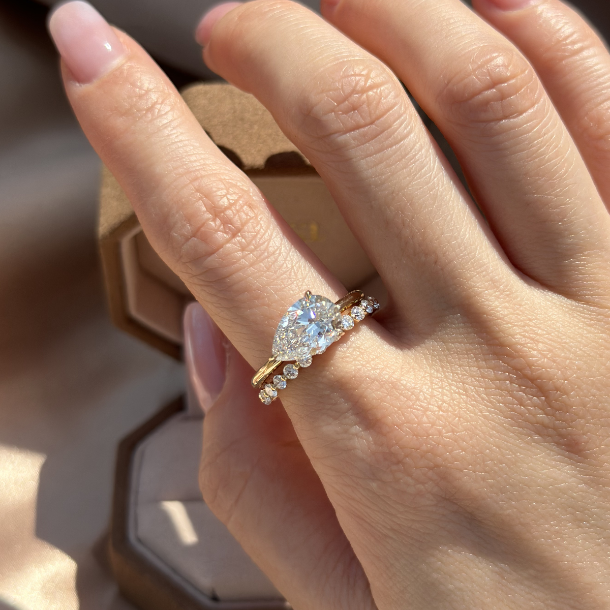 Top angle of stacked ring look featuring a pear diamond ring and a slim pavé band