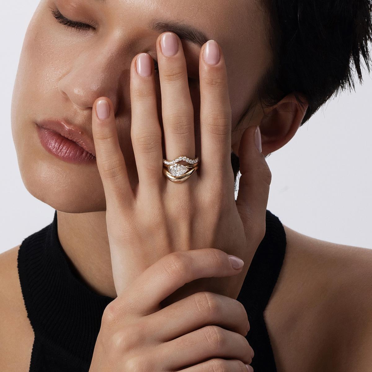 Triple-stack ring styling with pavé, curved bands, and an East West Pear diamond ring on finger