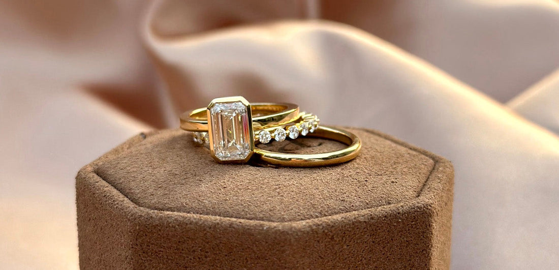 An emerald cut engagement ring and delicate gold bands. Each ring can also be styled as a pinky ring, offering versatility and modern elegance.
