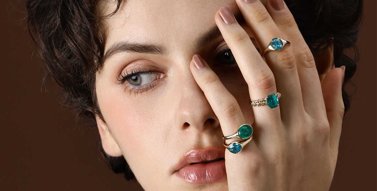 Model showcasing rings from Elora's Blue Gemstone collection featuring vibrant blue stones.