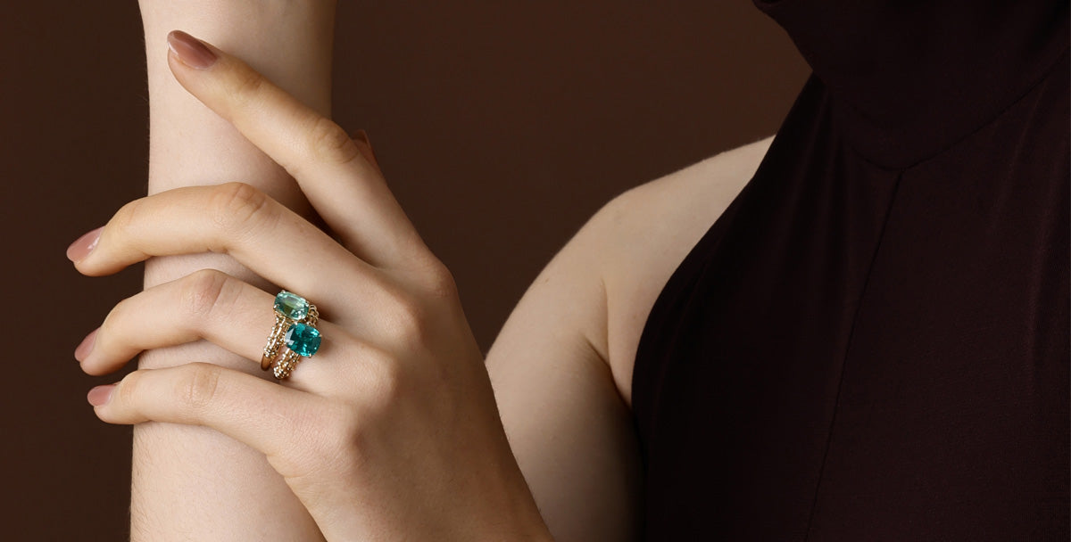 Hand wearing elegant rings featuring green gemstones, showcasing the beauty of Green Gemstone in luxury fashion.
