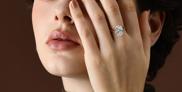Model wears a prominent gold oval cut lab diamond ring on her middle finger set.