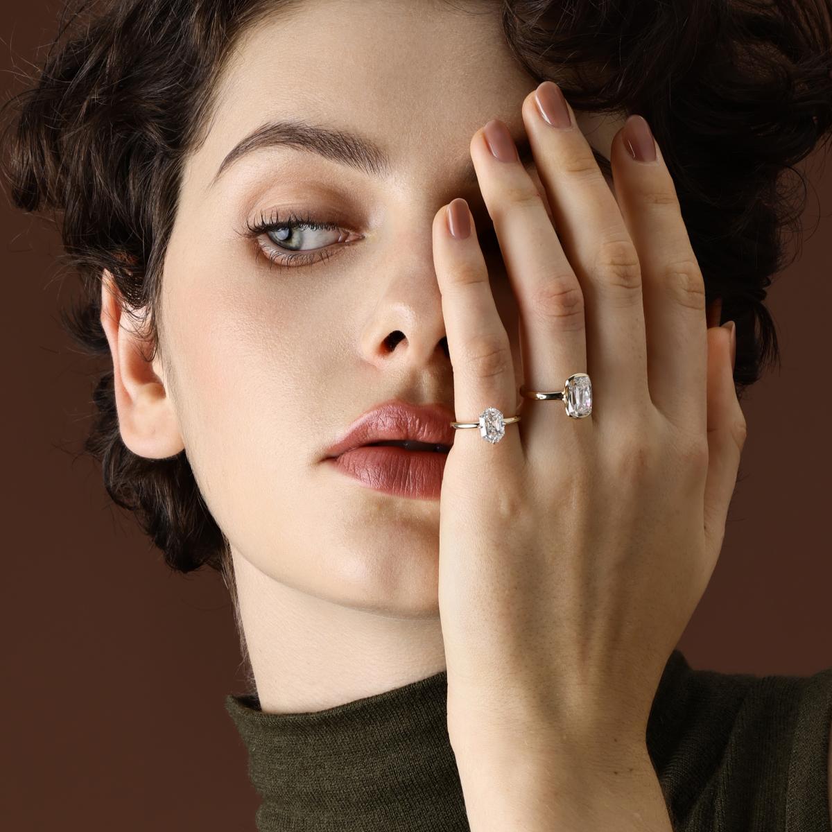 Old mine cut lab grown diamond engagement ring worn on hand with an emerald cut diamond pinky ring
