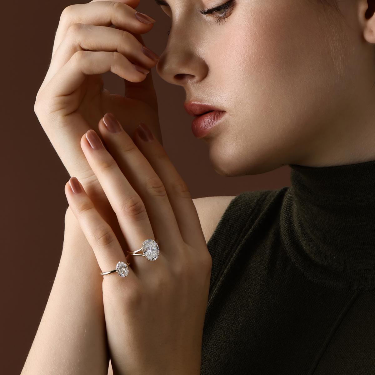 Oval cut lab grown diamond engagement ring shown on hand with an octagon shaped emerald cut diamond ring