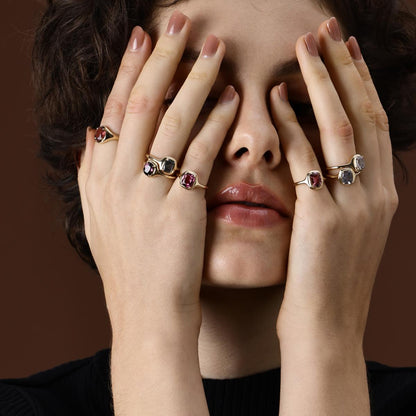 Model wearing cushion cut gemstone rings in different colors