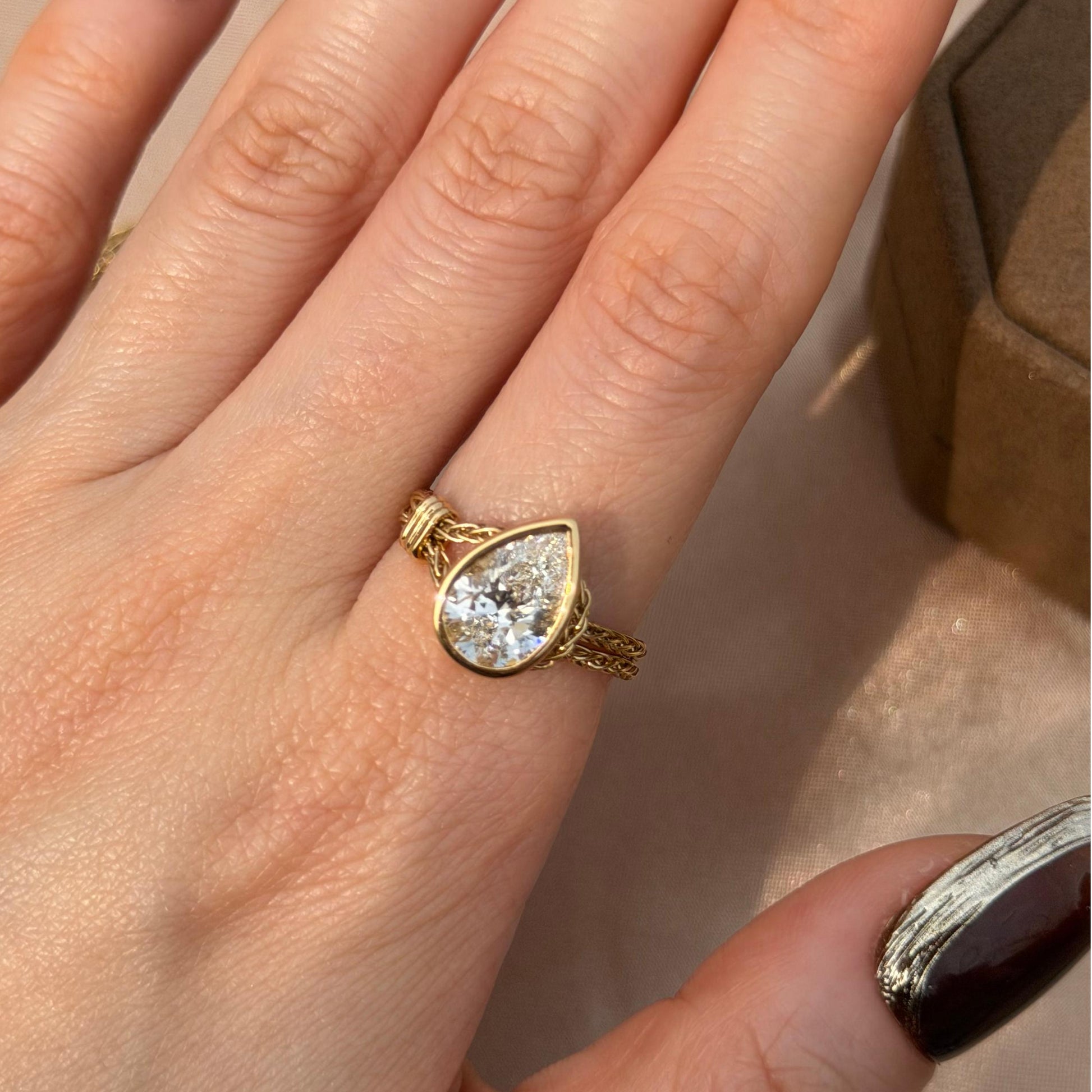 Faith-Pear Cut Lab Grown Diamond Engagement Ring on a hand with a gold chain design.