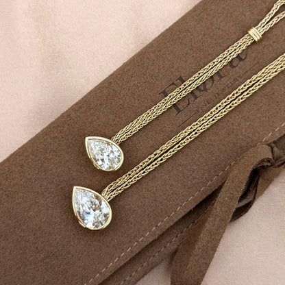 Faith-Pear Cut Lab Grown Diamond Engagement Ring featuring two pear cut diamonds on a golden chain background.