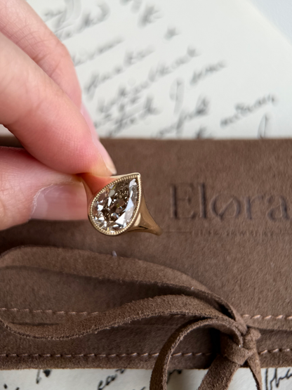 Eddy-Champagne Old Mine Pear Lab Grown Diamond Ring held against a soft background with elegant script.