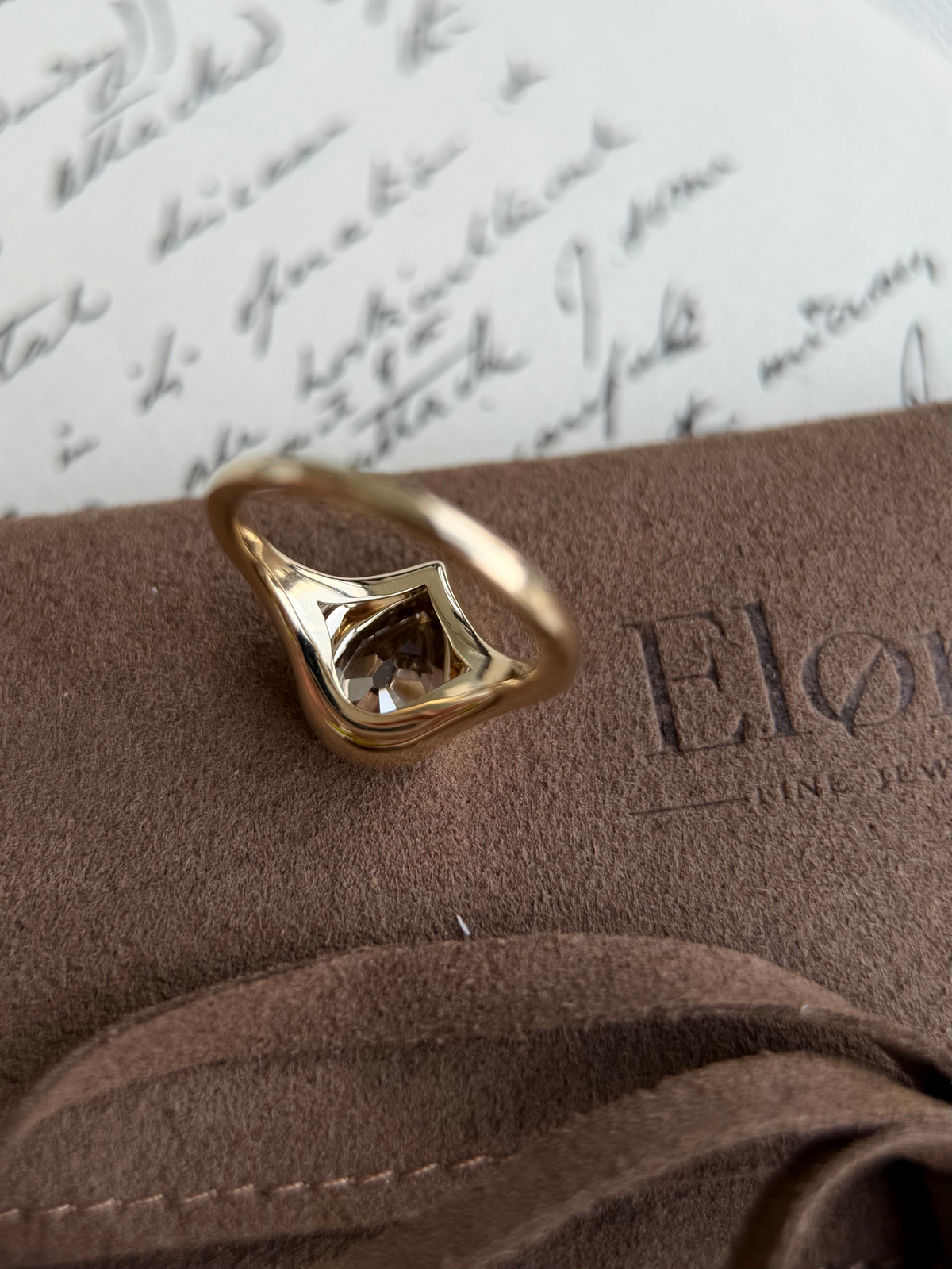 Eddy-Champagne Old Mine Pear Lab Grown Diamond Ring on suede background with antique letter in soft focus.