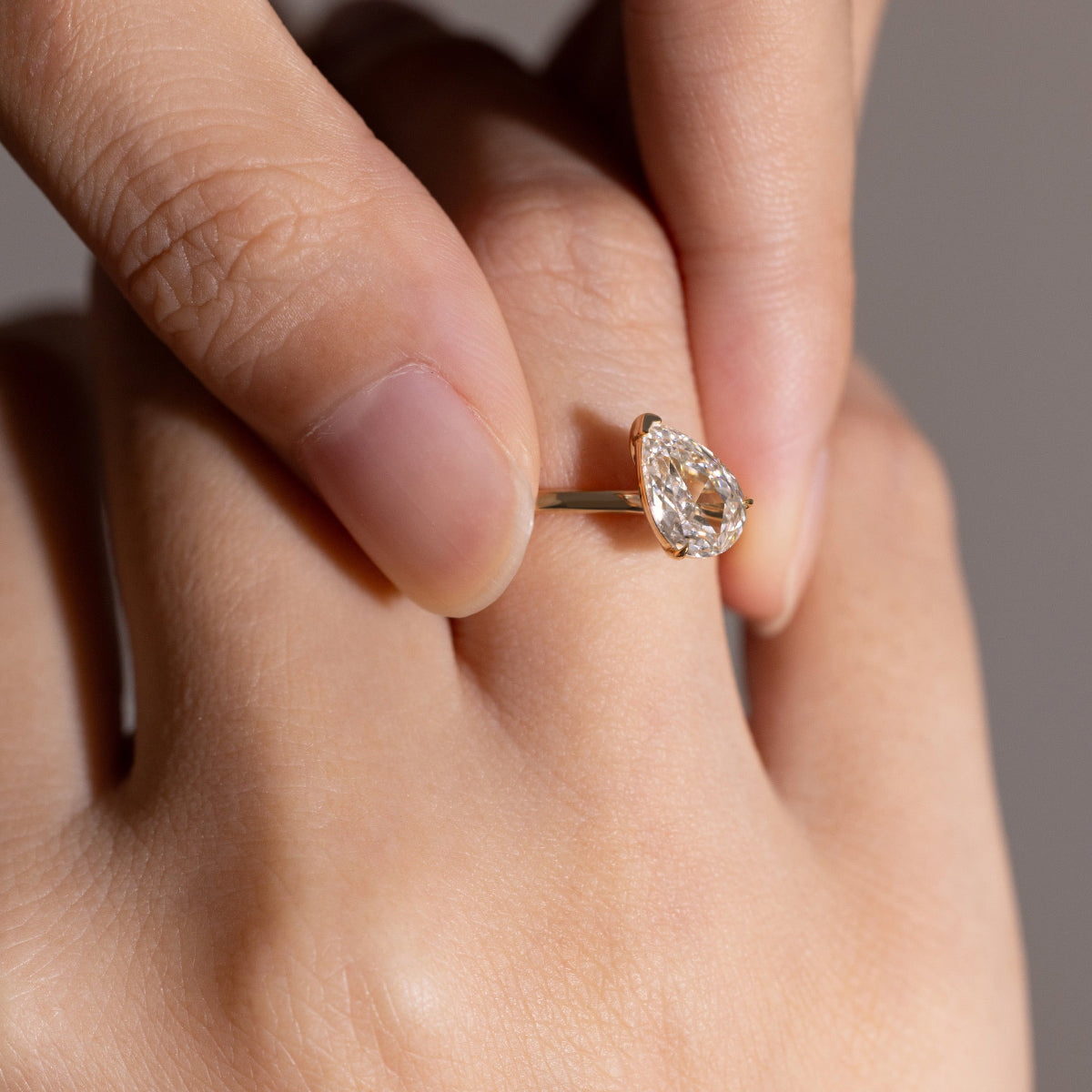 Close-up detail of tilted Pear cut diamond solitaire ring in 14K gold