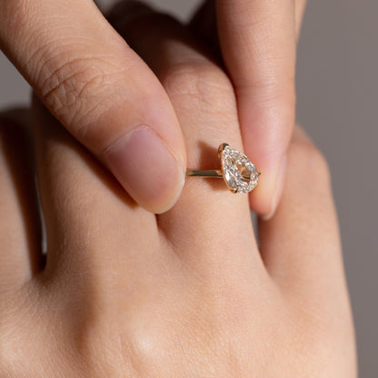 Close-up detail of tilted Pear cut diamond solitaire ring in 14K gold