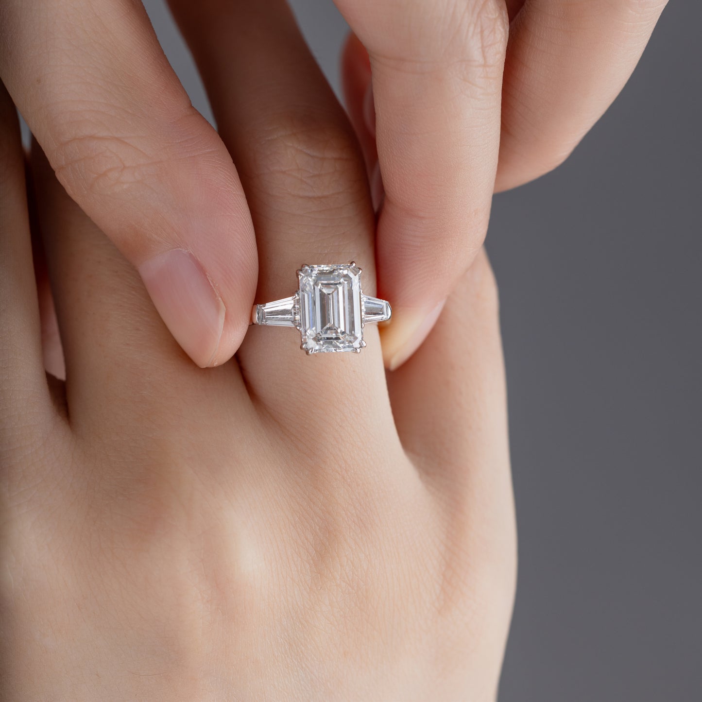 Close-up of Emerald cut Lab Grown diamond Three Stone Engagement Ring on model’s finger