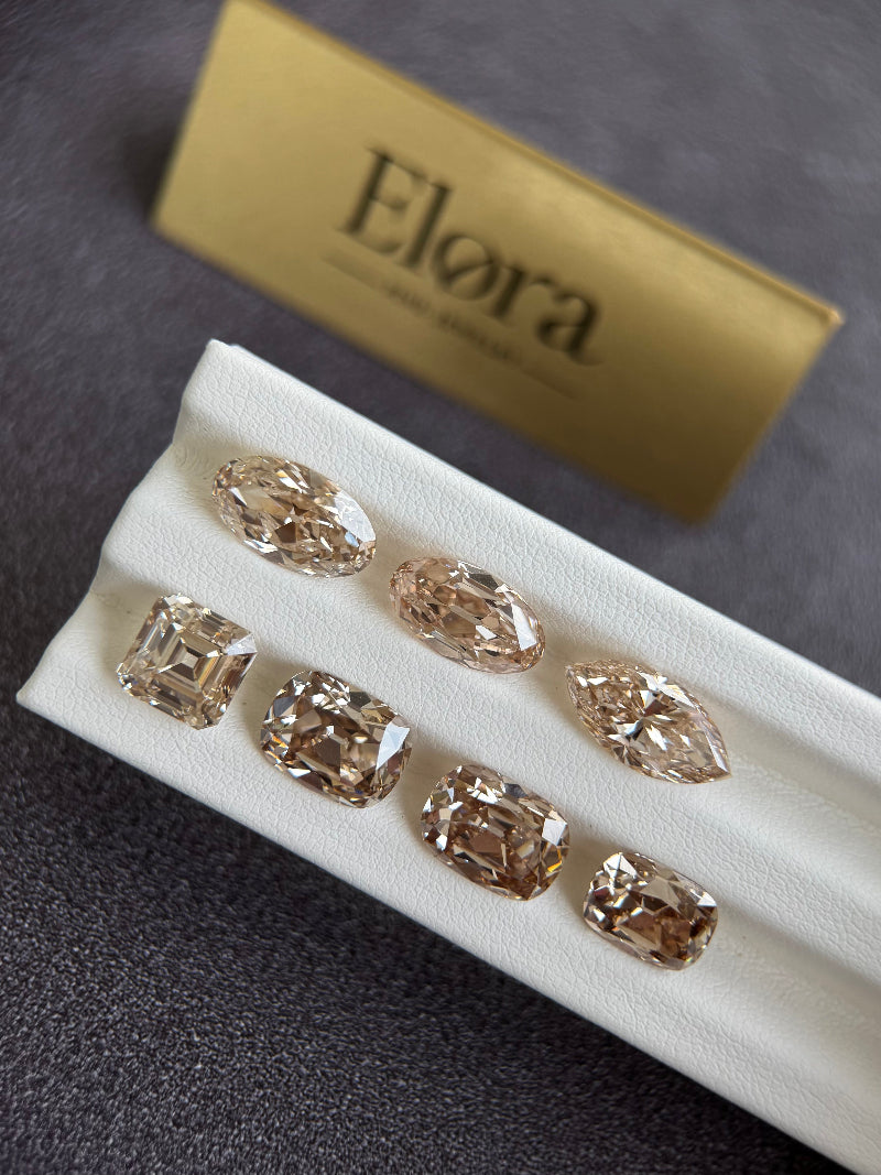 Set of diamond earrings on a white display with 'Elora' branding in the background.