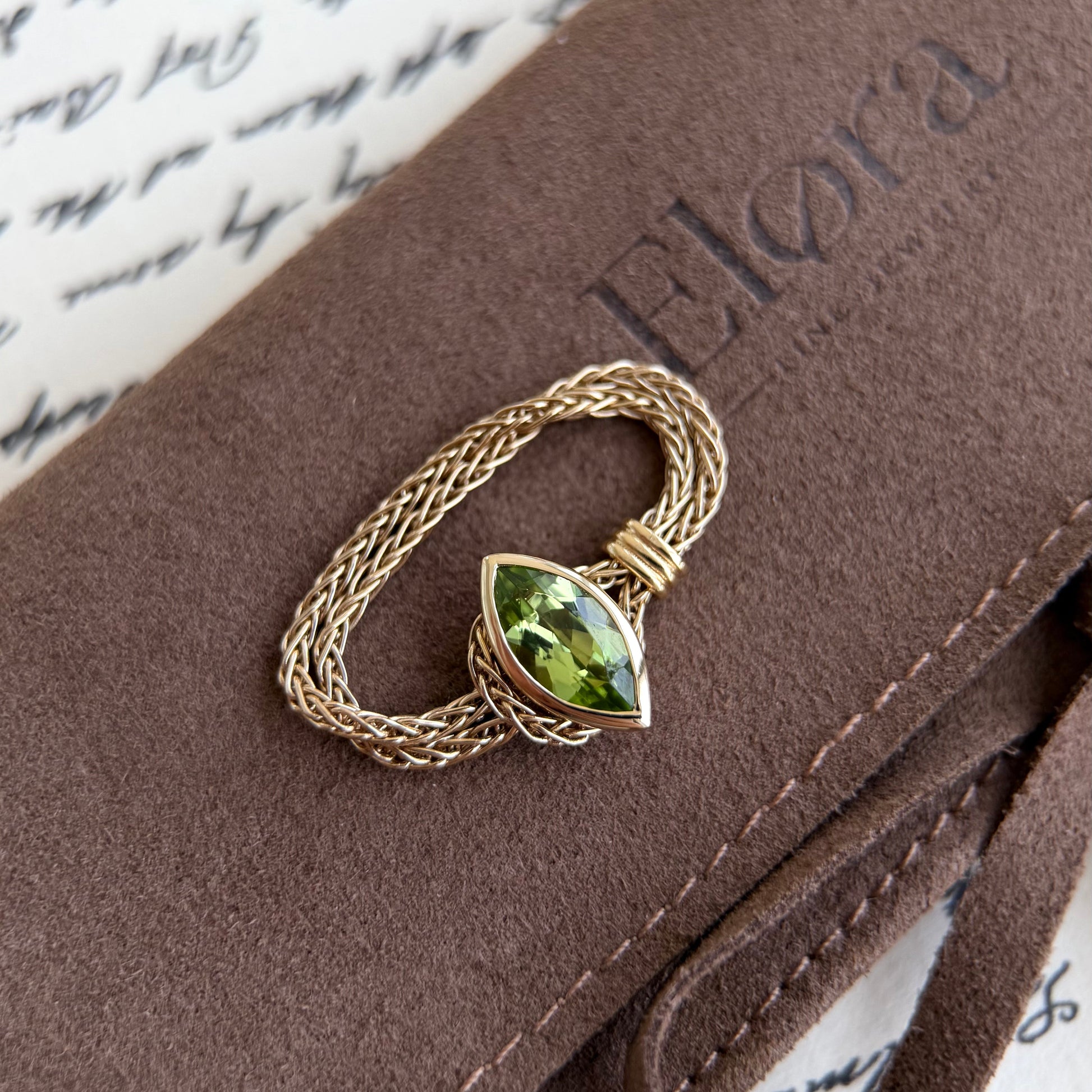 Faith-Marquise Cut Natural Peridot Gemstone Chain Ring atop a stylish Elora jewelry case, showcasing its elegant design.