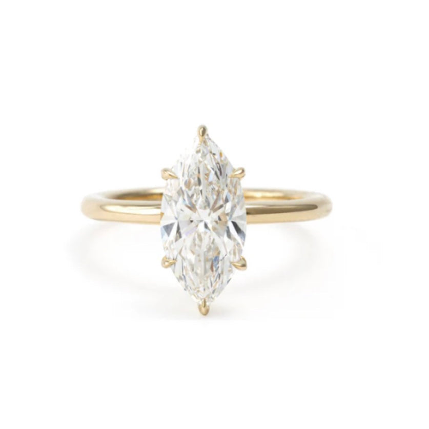 A yellow gold ring featuring a marquise-cut diamond solitaire setting on a clean white background.
