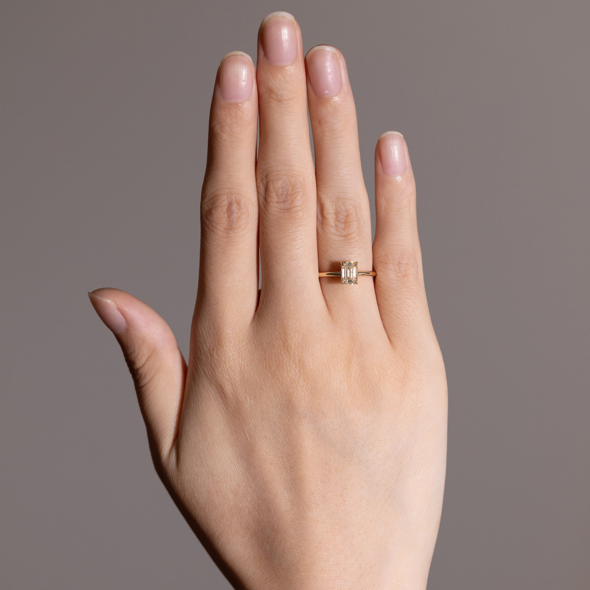 Hand shot Heather Emerald Cut Lab Diamond Engagement Ring with angular solitaire style