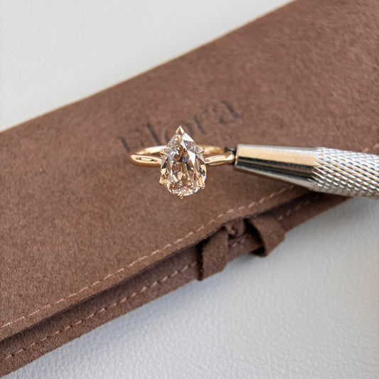 Alfa-2.76 Champagne Old Mine Pear Lab Grown Diamond Ring displayed on brown fabric with a tool.
