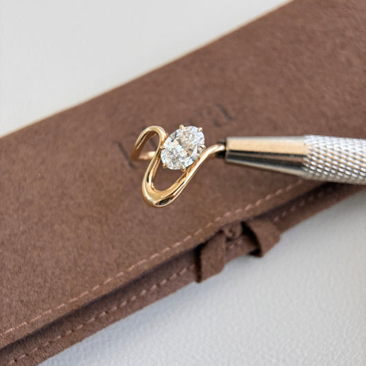 Iris-1ct Oval Cut Lab Grown Diamond Pinky Ring showcased with a golden bypass design on a brown surface.