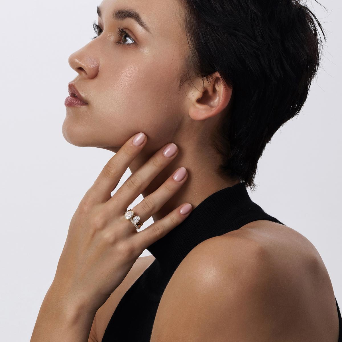 Model showcasing Aria tilted oval cut diamond ring with multiple gold stacking rings