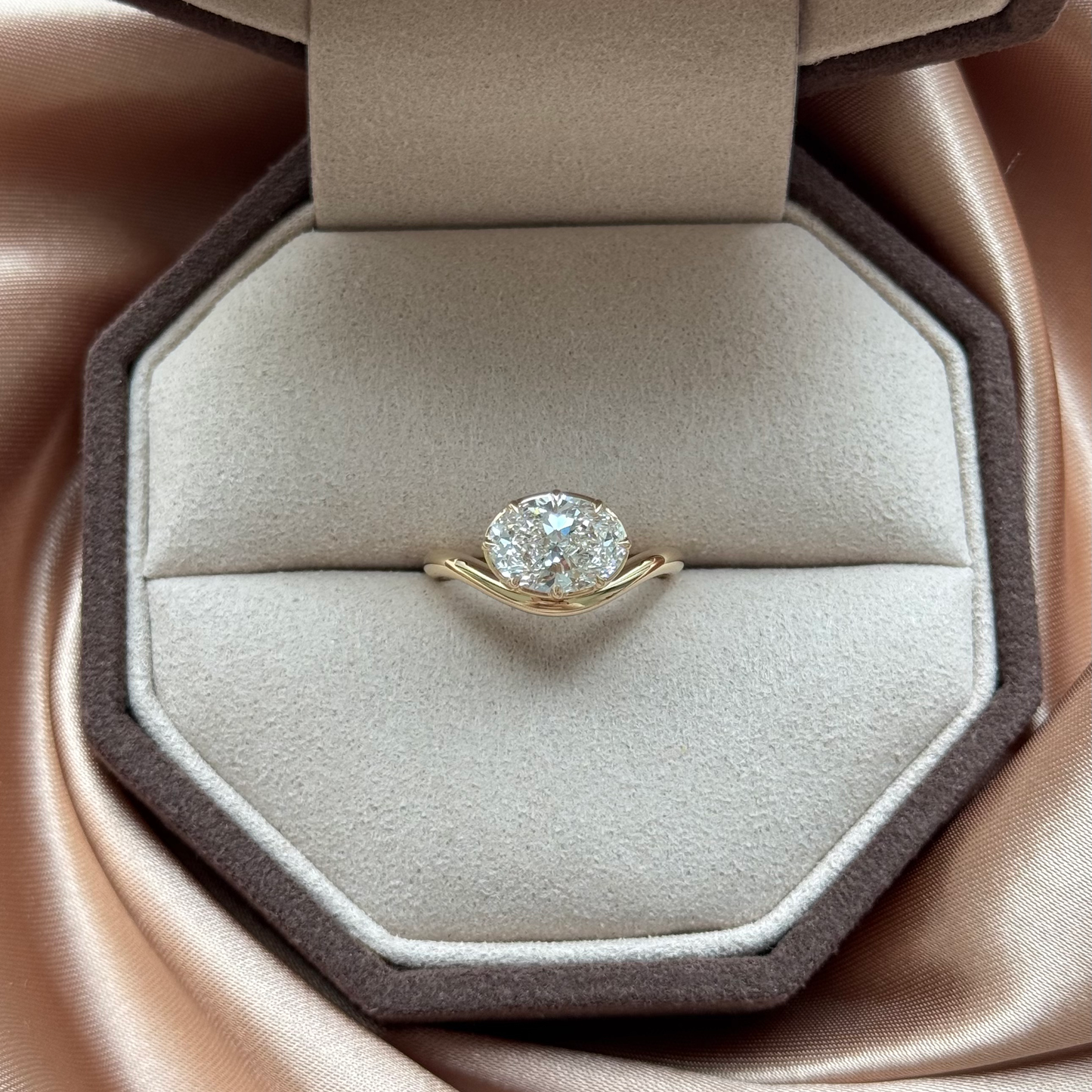Wave-Oval Cut Lab Grown Diamond Engagement Ring on a plush display cushion.