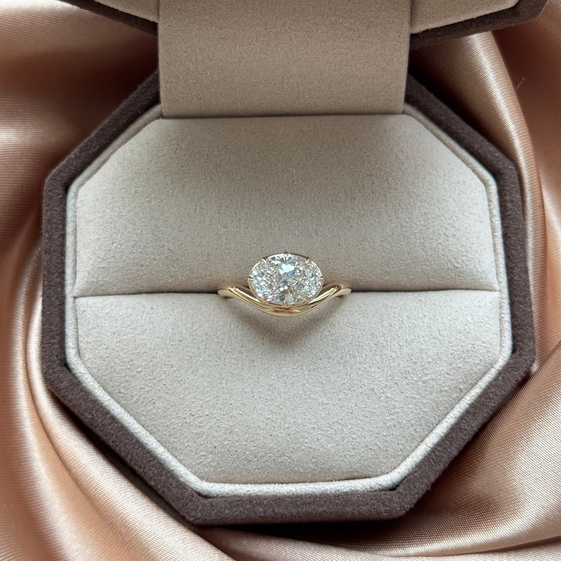 Wave-Oval Cut Lab Grown Diamond Engagement Ring on a plush display cushion.