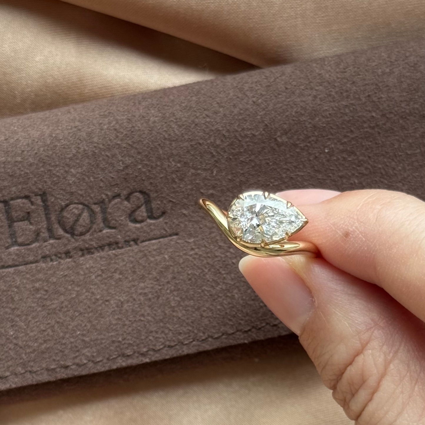 Wave-Pear Cut Yellow Gold Lab Grown Diamond Engagement Ring held in hand, featuring a pear cut diamond in a sleek setting.